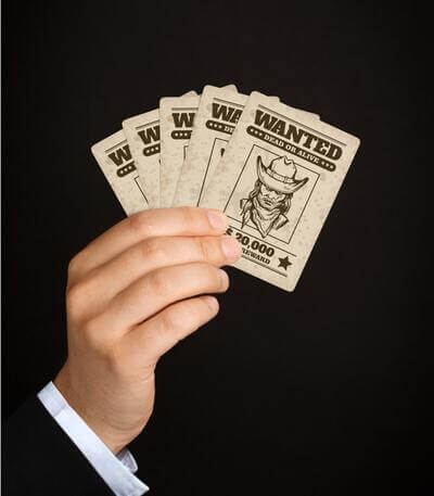 Hand of cards displaying a custom design of a spaghetti western-style wanted poster of a renegade cowboy with a bounty.