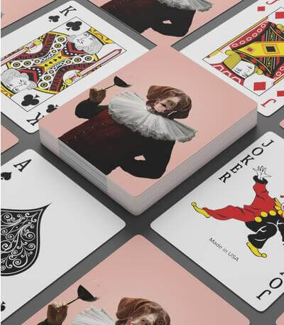 Spread-out deck of playing cards with a custom print of an upright beagle in a noble’s ruff and coat holding a glass of wine.