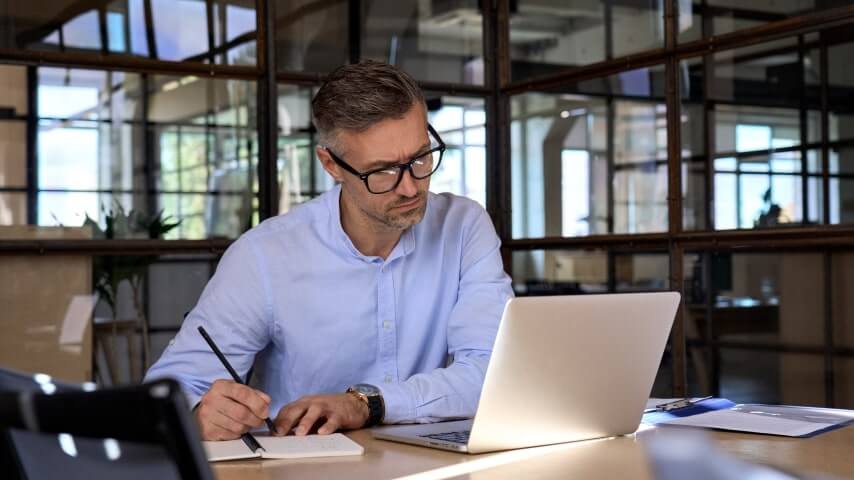 Man doing work on market research at his desk to earn extra money online.