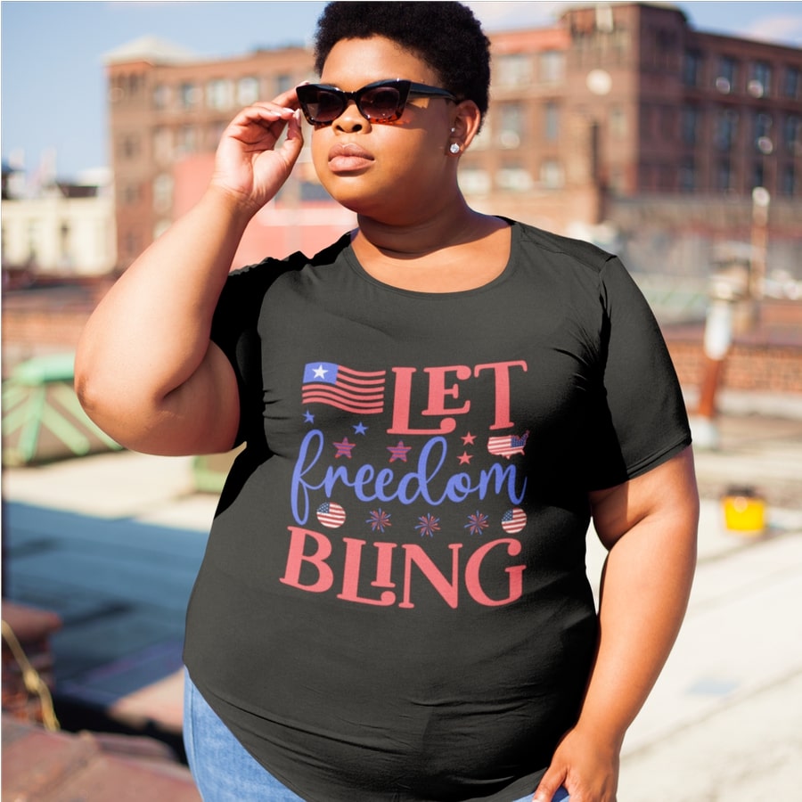 Model in sunglasses wearing a plus-sized custom t-shirt with a stylized slogan “Let Freedom Bling” printed on the full front.