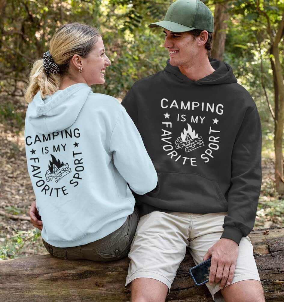 An image of a couple wearing custom hoodies with camping-related text.