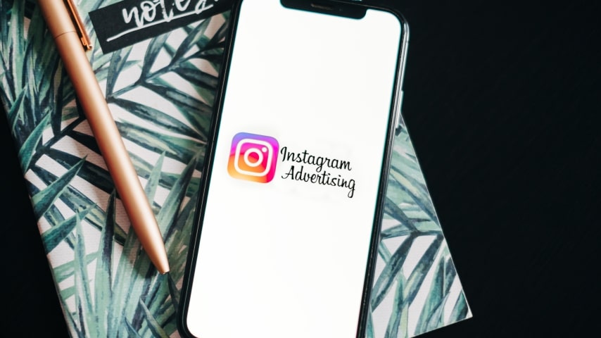 Phone with “Instagram Advertising” shown on the screen placed on top of a notebook.