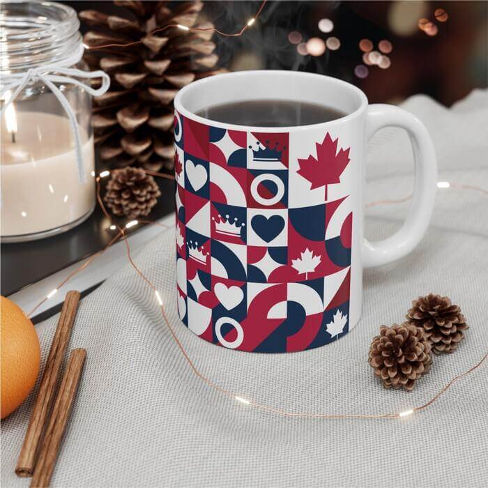 Winter-inspired scene featuring a coffee mug adorned with a pattern resembling the Canadian flag, nestled amidst pinecones, cinnamon sticks, and a softly glowing candle on a table