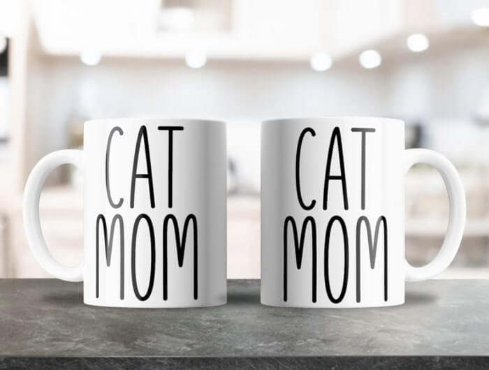 Two white mugs with large text saying “Cat Mom.”