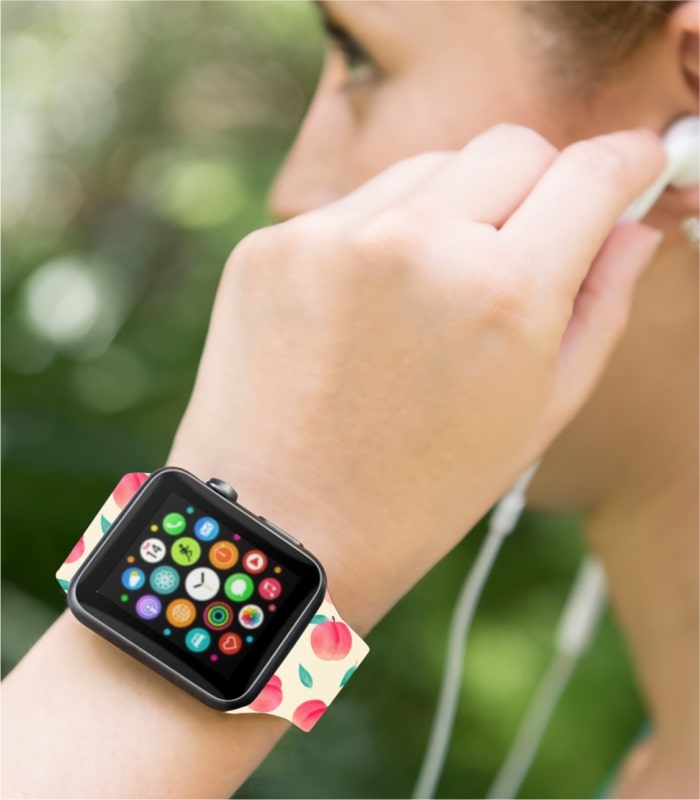 An image of a woman wearing a custom Apple Watch band with a peach pattern.