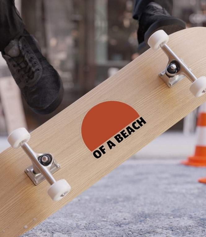Large sticker on a skateboard of an image of the sun and the text “Of a Beach” underneath.