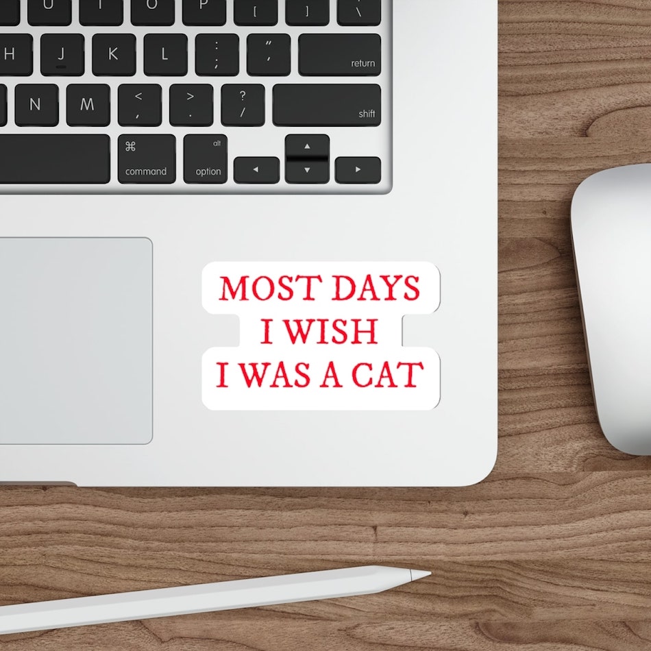 White die-cut sticker with red text saying, “Most days I wish I was a cat.”