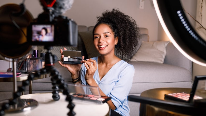 Young woman filming branded content for Instagram Reels where she is holding up and reviewing an eyeshadow palette.