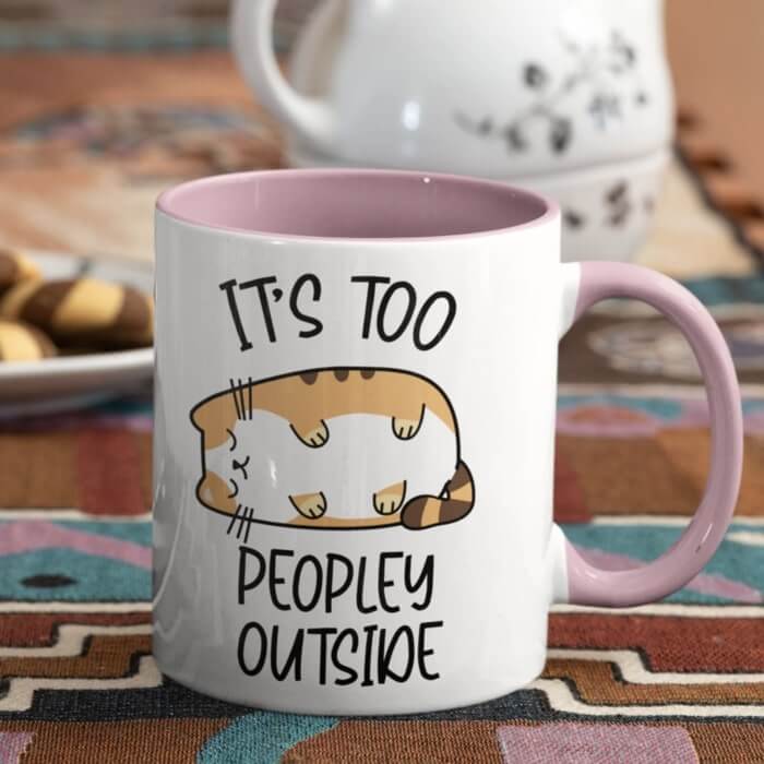 Pink accent mug with a design of a sleeping chubby cat and the caption “It's too peopley outside.”