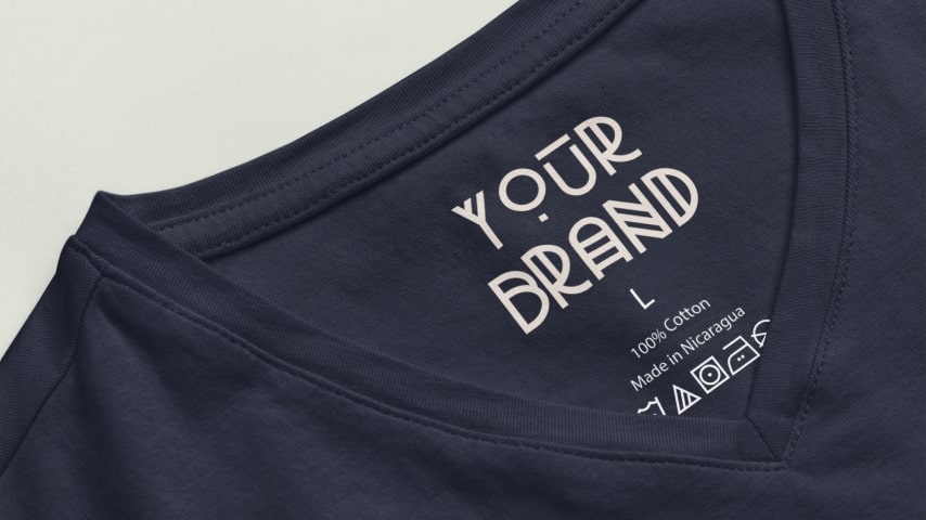 Closeup of a black t-shirt's neck label area with care instructions, size, and “Your Brand” placeholder text.