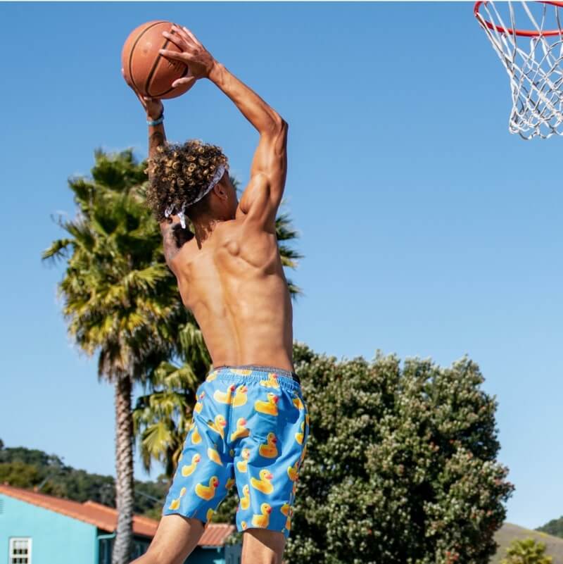 An image of a man dunking a basketball while wearing custom basketball shorts with a duck print.