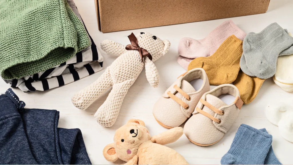A box filled with baby clothes, a teddy bear, and various baby items arranged neatly inside.