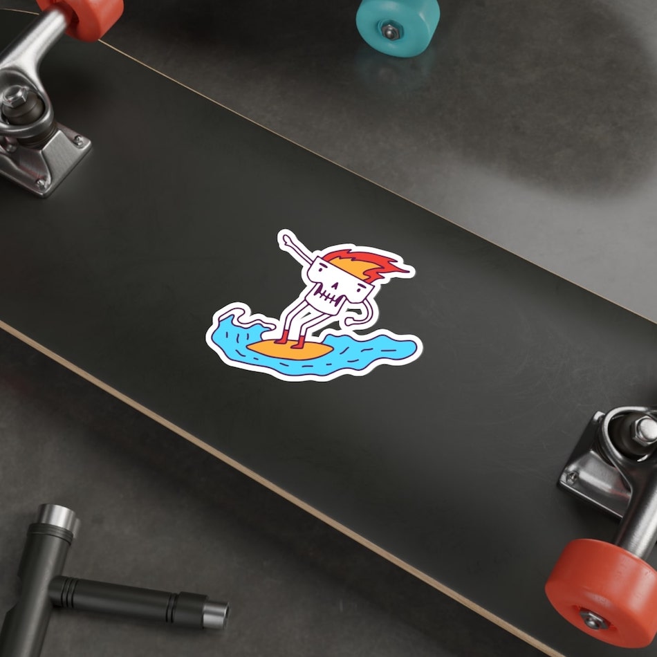 Large personalised sticker on a skateboard of a surfing skull with fire coming out of its scalp.