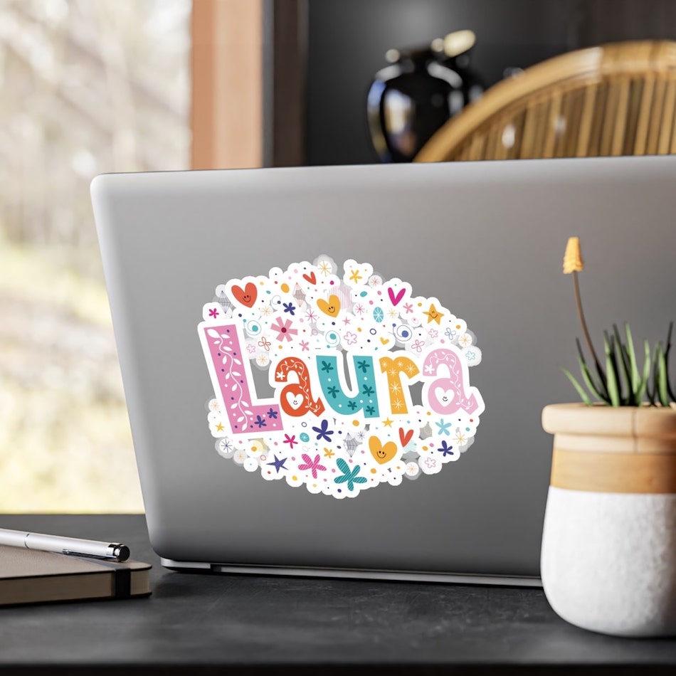 Large kiss-cut sticker on a laptop of the name “Laura” and a detailed design of small hearts and flowers.