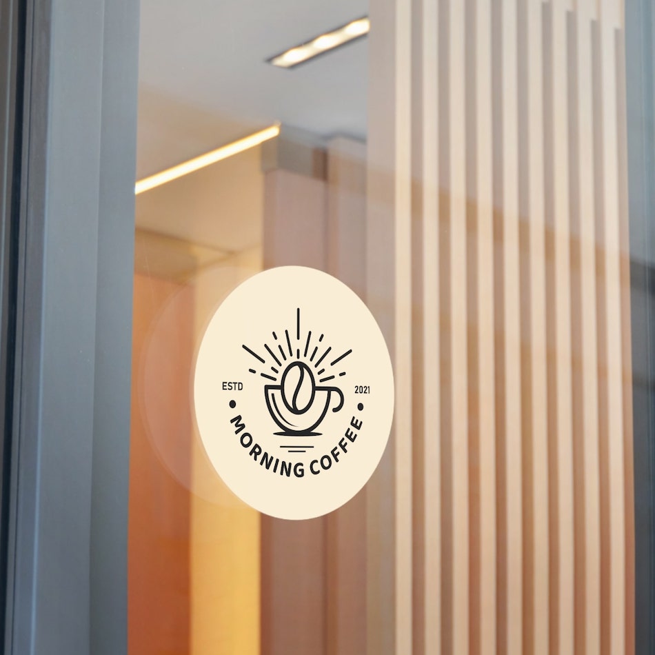 Large round sticker on a glass door with a logo of a coffee cup and the text “Morning Coffee” underneath.