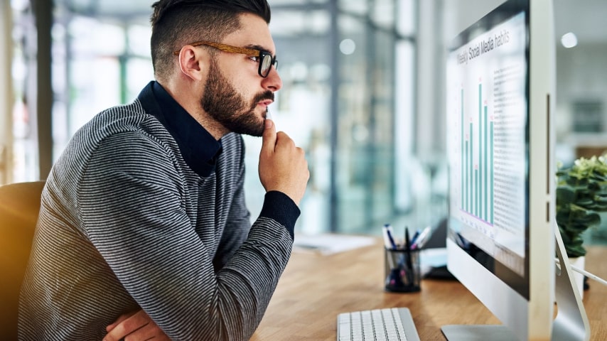 Man sitting in front of a computer screen and looking at analytics.