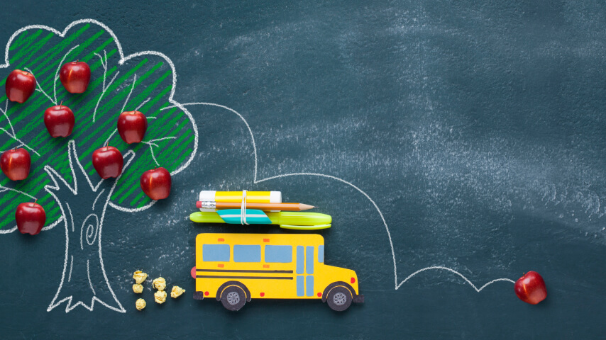 An image on a chalkboard with a school bus next to an apple tree carrying school supplies