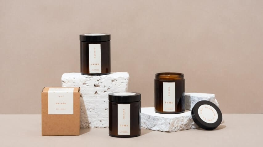 A collection of candles in jars with minimalistic labels and packaging.