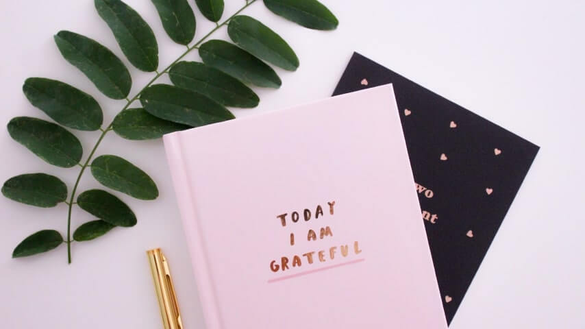 A journal with a soft pink cover and the text “Today I am Grateful” printed in the middle.