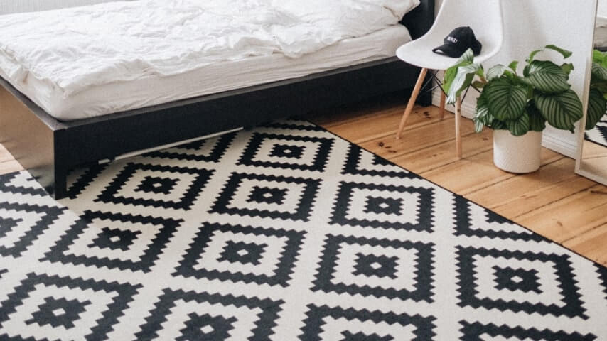 Large white rug printed with a pattern of black geometric shapes.