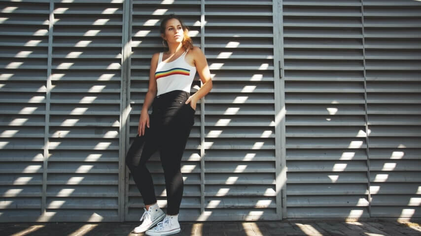 Woman wearing a white tank top with a rainbow line printed across the chest.