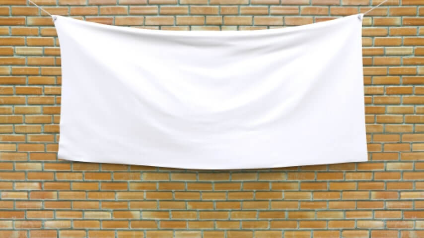 A blank tapestry hanging in front of a brick wall.