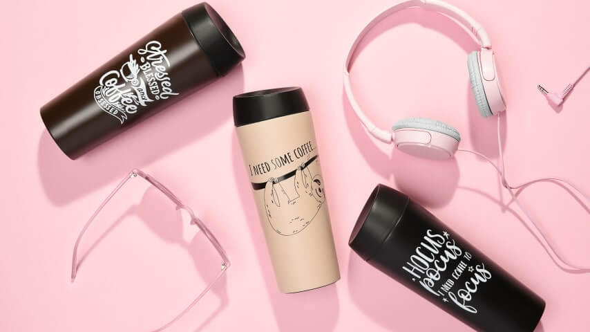 Three tumblers with designs saying “Stressed, blessed, and coffee obsessed,” “Hocus-Pocus, I need coffee to focus,” and “I need some coffee” above an image of a sloth.