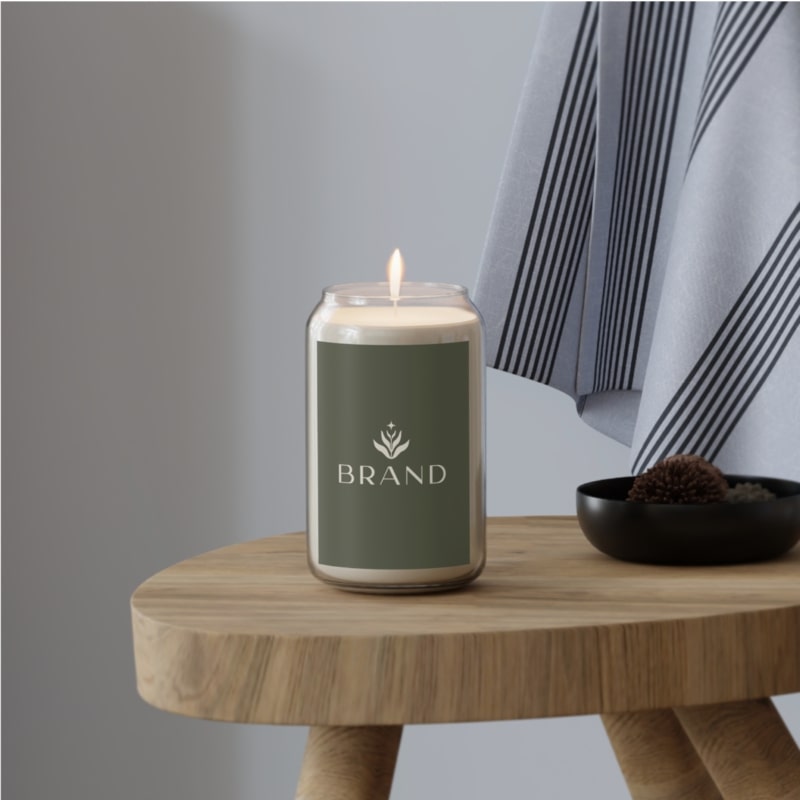 A candle on a table with a custom brand design on the label