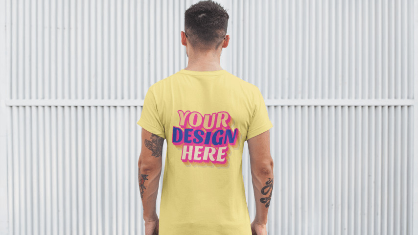 Man wearing a pale yellow t-shirt with a “Your Design Here” placeholder on the back print area.