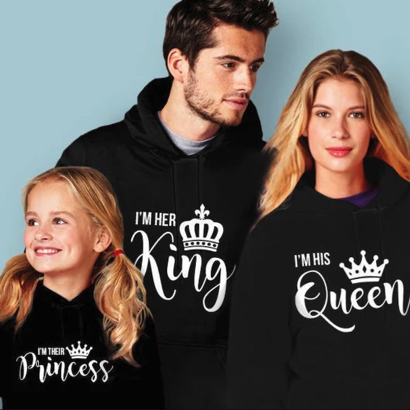 A family in matching black hoodies, the father's hoodie saying “I'm her king,” the mother's hoodie saying “I'm his queen,” and the daughter's hoodie saying “I'm their princess.”