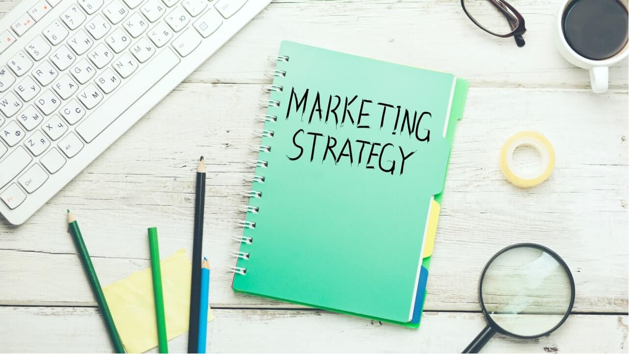 How to Print on a Mug – Promote Your Mug Printing Business A notebook on a table with “Marketing Strategy” written on the cover.