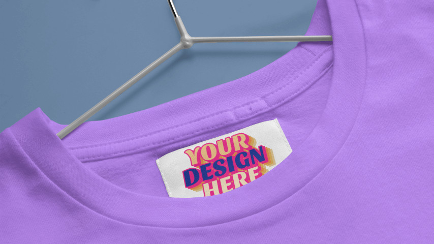 Purple t-shirt on a hanger with a “Your Design Here” placeholder on the inner neck label.