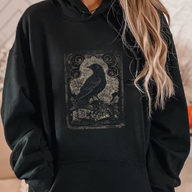 Black hoodie with a gothic design of a raven in front of an elaborate ornamentation.
