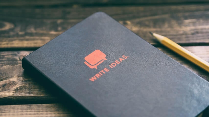 A black notebook with a design of red speech bubbles and the text “Write Ideas” underneath them.