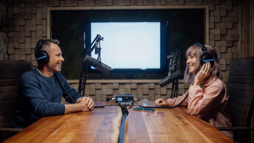 A man and a woman recording a podcast in a sophisticated recording studio.