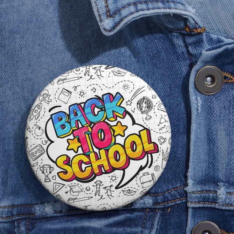 A "back-to-school" pin button with a black-and-white background pattern consisting of school essentials and symbols.