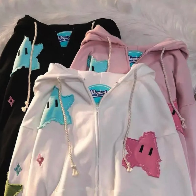 Y2K style hoodies in black, pink, and white colors, with a design of cartoon stars with cute eyes.