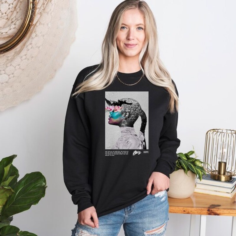Woman wearing a black sweatshirt with a collage design that forms an image of a woman's profile from various elements.