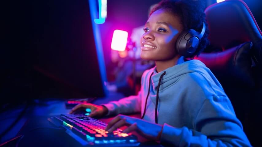 A woman with headphones and a neon-lit streaming setup sitting at her computer.