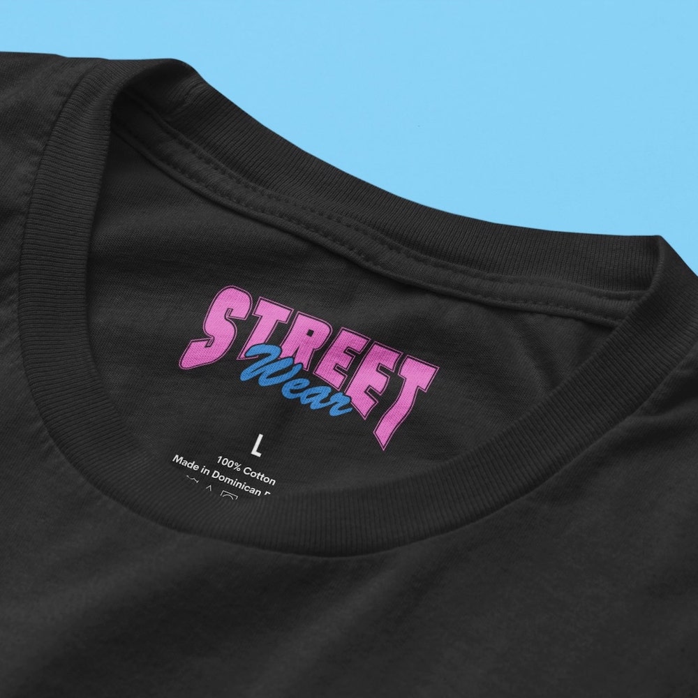 Black t-shirt with a custom branded neck label with a logo text saying “Street Wear” in pink letters above the size and material details.