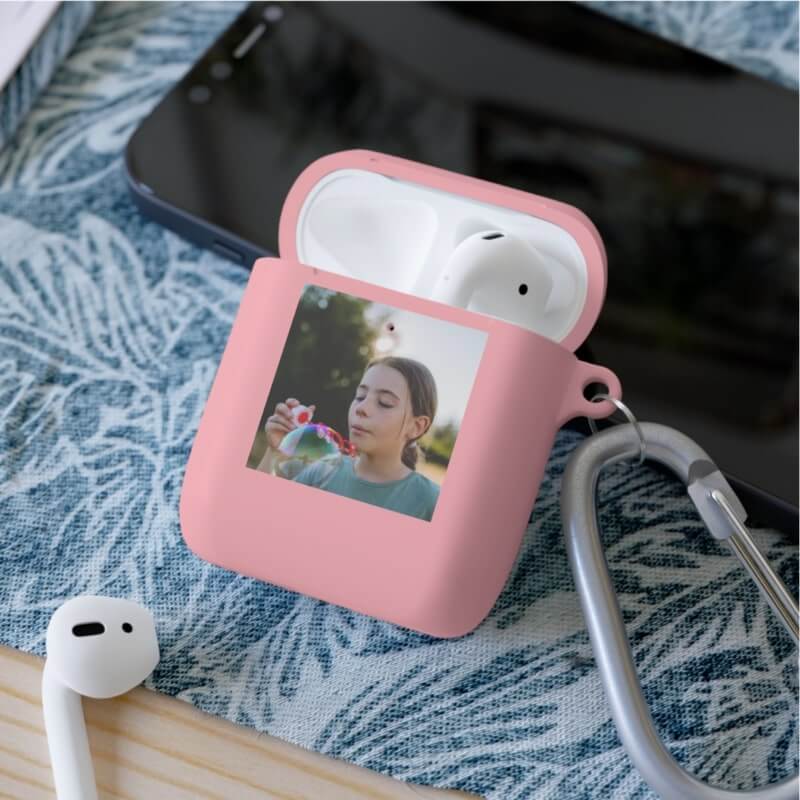 A trendy setup with a phone, AirPods, and a custom pink AirPod case with a photo printed on it.