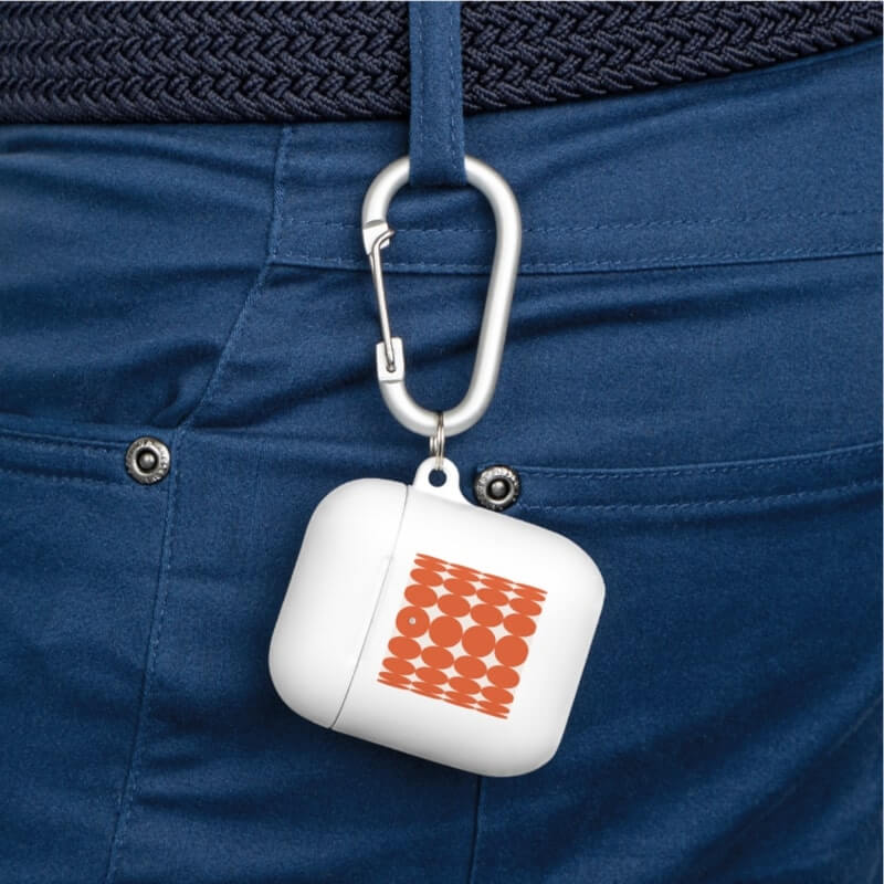 A white AirPod case hanging on a belt loop with a custom pattern design.