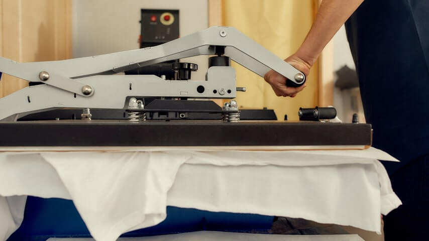 Person pressing a design on a white t-shirt with a heat press.