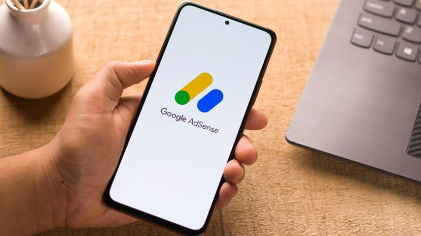 Person holding a phone with a Google AdSense logo on the screen.