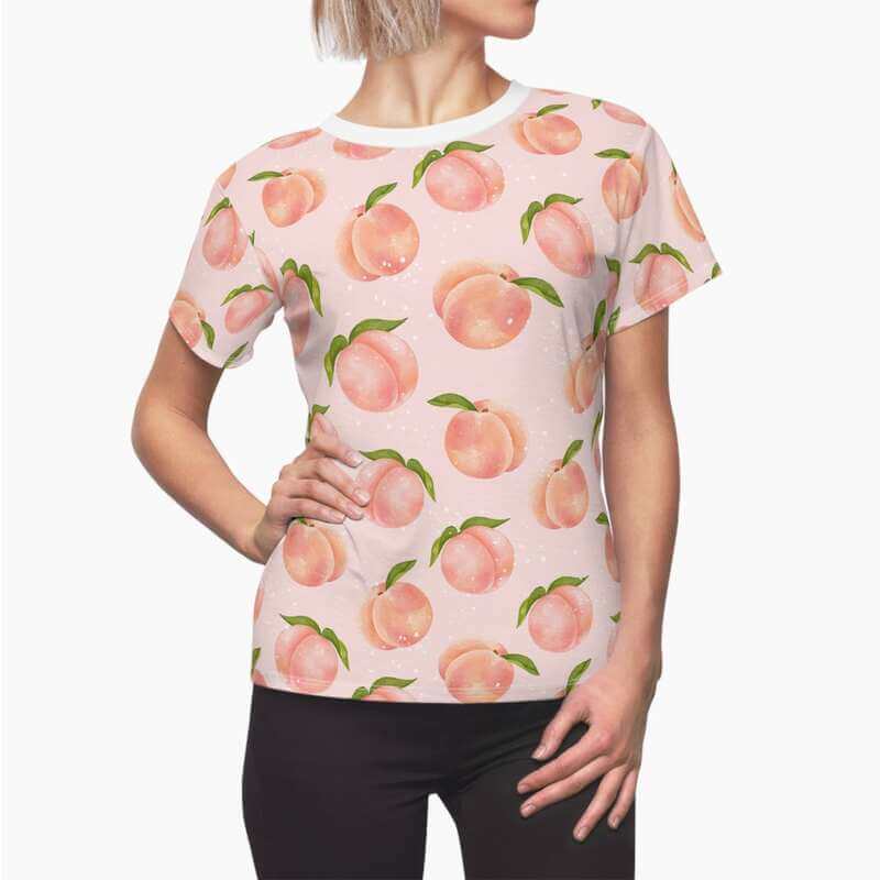 A mockup image of a woman wearing a unisex custom all-over-print t-shirt with a peach print.
