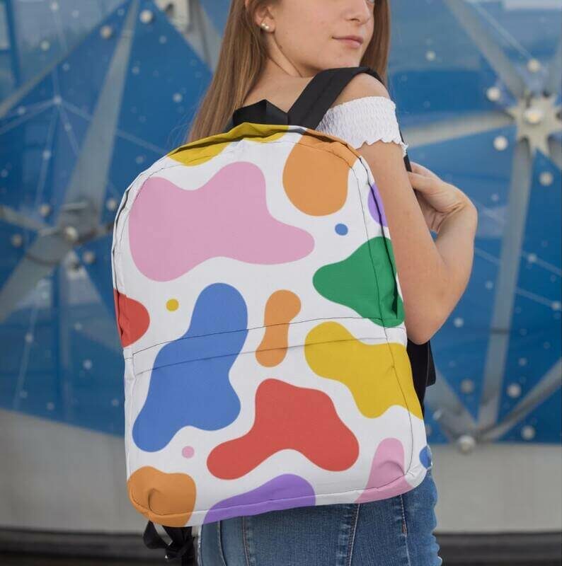 A girl wearing a custom backpack with abstract multi-color blobs as part of her school apparel.