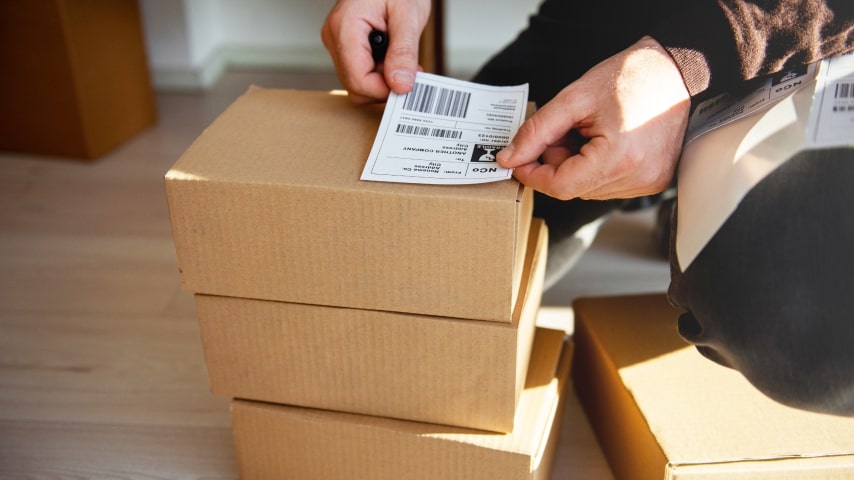 A person placing a shipping label on a package.