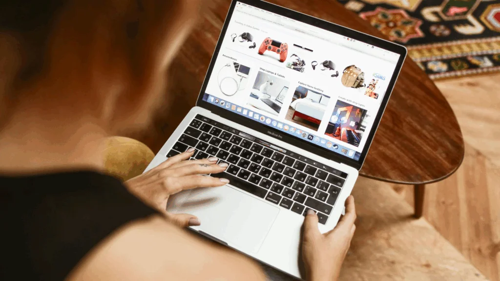  A woman is focused on her laptop, browsing a shopping website with various products displayed on the screen.