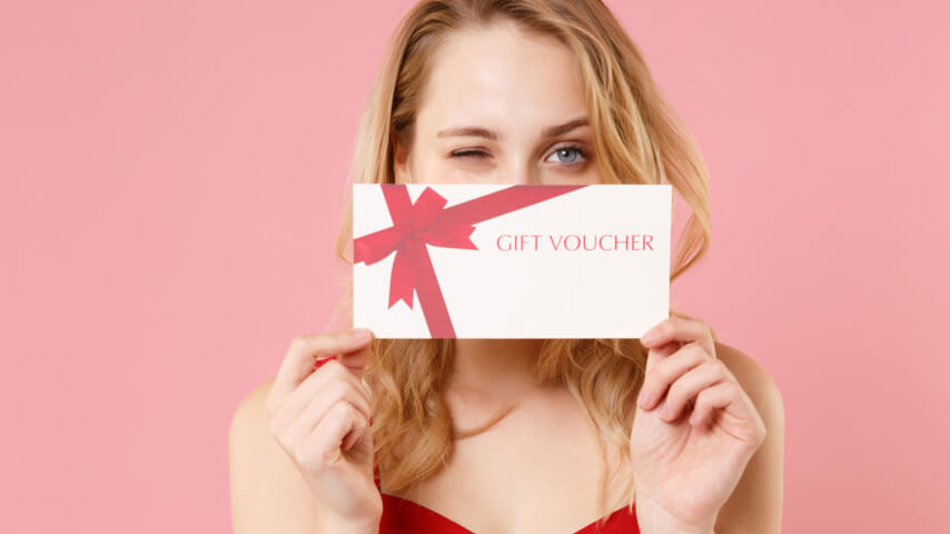 A woman holding a gift voucher, promoting holiday sales.