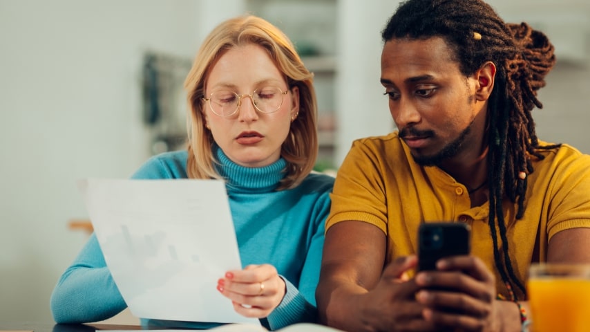 A man and a woman thoughtfully looking at a phone screen.